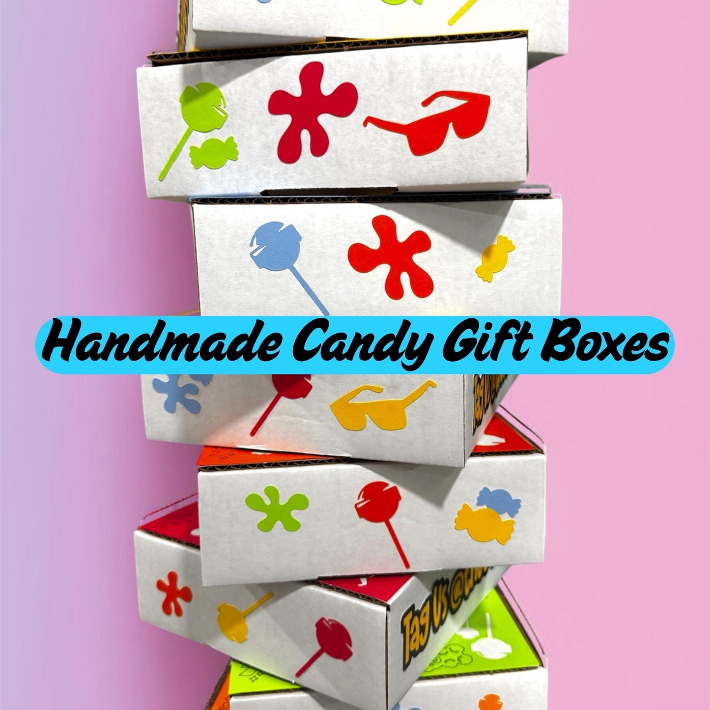 Stack of handmade candy gift boxes with colorful designs on a pink background