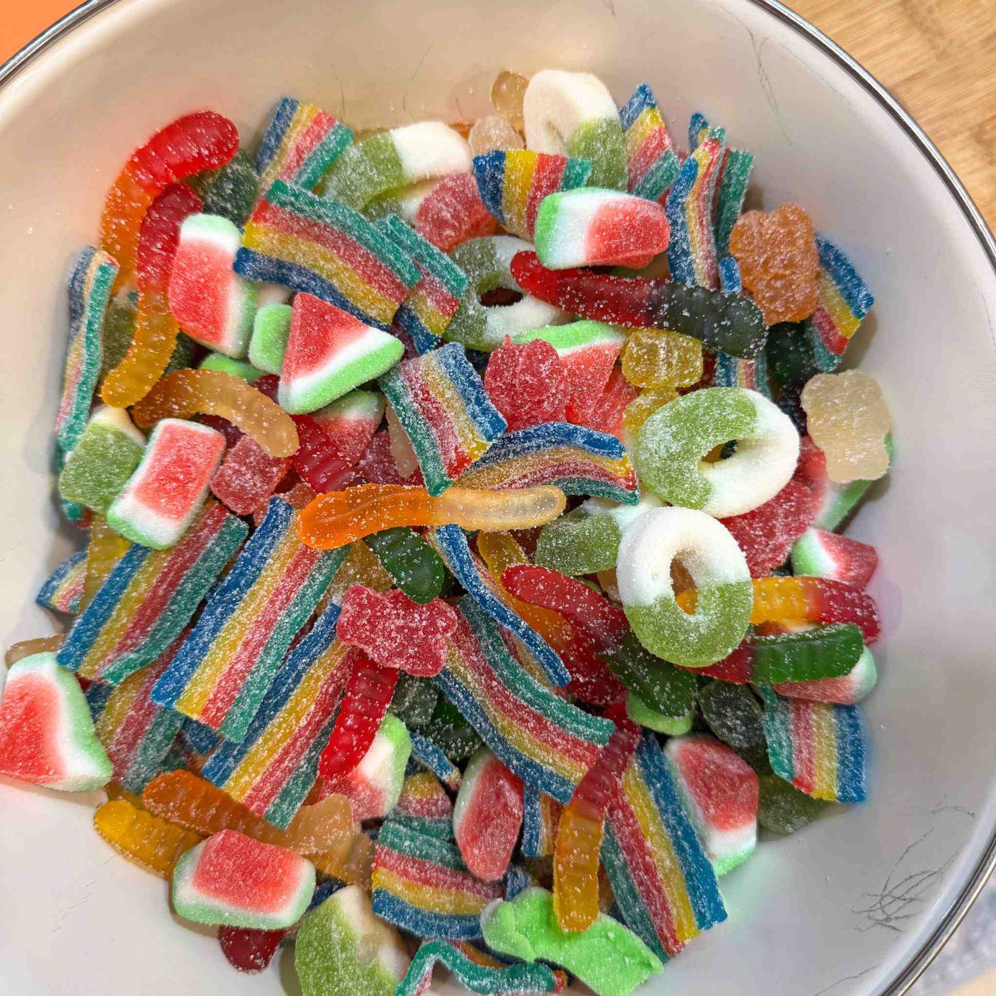 Bowl of mixed sour gummy candies including rainbow belts, watermelon wedges, and gummy rings
