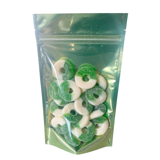 Close-up of sugar-coated green apple gummy rings, half white and half green, with a chewy texture and sour-sweet flavor